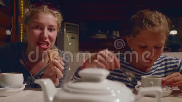 两个年轻的白种人女孩在远足后晚上在咖啡馆喝茶和开玩笑视频的预览图