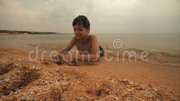 男孩躺在海浪里玩沙子视频的预览图