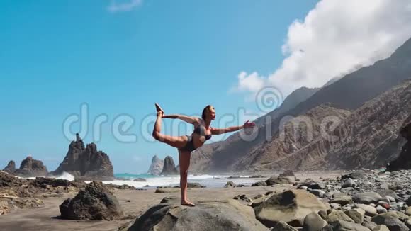 穿着紧身衣的年轻女子在令人惊叹的日出时在海面上的海滩上练习瑜伽健身运动瑜伽和健康视频的预览图