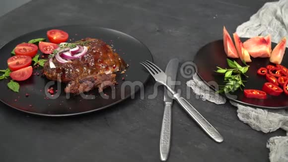 黑盘上摆着一个牛肉里面放着酱汁和洋葱放着罗勒切的西红柿一个番茄和桃子切片视频的预览图