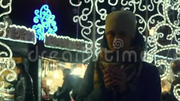 在圣诞集市上喝热茶想保暖的冻僵的年轻女人视频的预览图