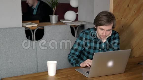 团队合作两个微笑的年轻商人坐在办公室的桌子上工作桌子上有笔记本电脑智能手机平板电脑视频的预览图