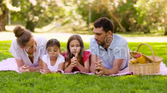 一家人躺在夏日公园的野餐毯上视频的预览图