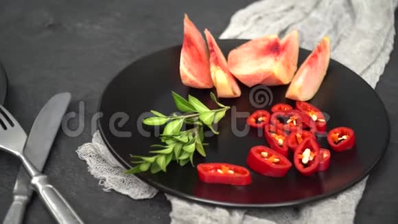 在一个黑色的盘子上是一个番茄和桃子切片旁边是一个迷迭香枝旁边是一个刀叉视频的预览图