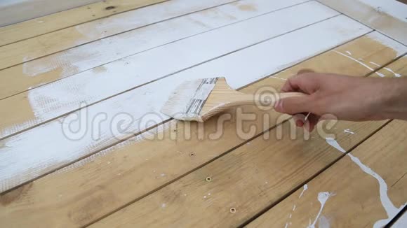 工人手握毛笔在木露台天然木地板或墙面纹理表面涂刷白色视频的预览图