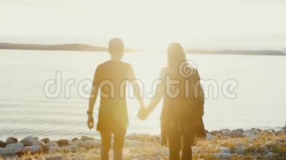 恋爱中的男女青年夫妇在岩石海滩上水边游去视频的预览图