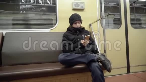 一个穿冬天衣服的人在地铁里用智能手机那个年轻人坐在地铁里上网视频的预览图