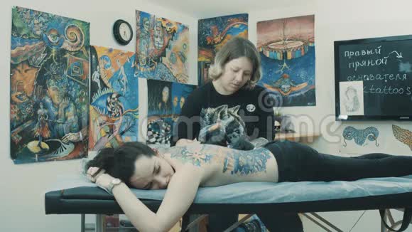 纹身师在女孩背上做纹身视频的预览图