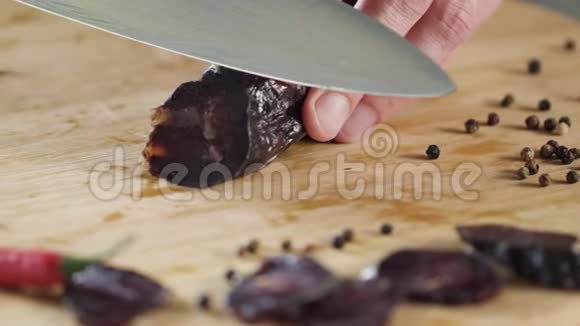 特写刀切香肠场景木切割板上切割深色腊肠的特写盐的背景视频的预览图