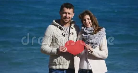 一对夫妇在海上展示心形红纸视频的预览图