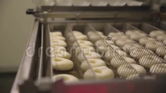 在一个小镇的甜甜圈面包店制作甜甜圈的程序甜甜圈在油炸锅里油炸场景准备过程视频的预览图