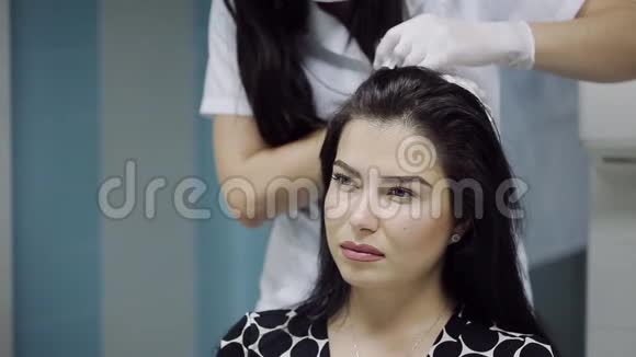 一位美丽的年轻女子在美学医学的中心接受头部注射预防和治疗视频的预览图