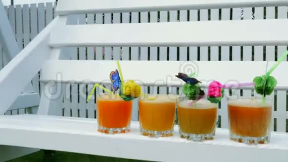 特写镜头在白色的木秋千上在花园里在夏天4杯新榨的橙汁和桃子汁视频的预览图
