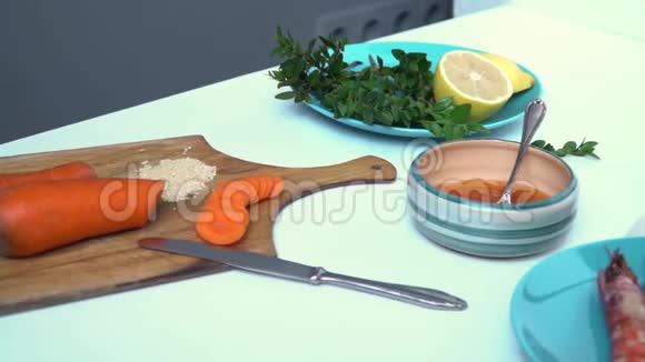 切好的胡萝卜加一片芝麻放在盘子里酱油加酱青菜加柠檬炸老虎虾放在蓝色的盘子里视频的预览图