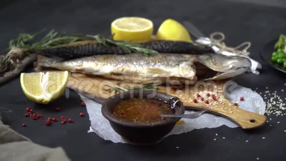 砧板上的炸鱼旁边是迷迭香柠檬侧肠和一个带有蔬菜装饰的盘子视频的预览图