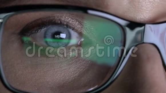 戴眼镜的特写女人的眼睛在晚上的笔记本电脑上工作视频的预览图