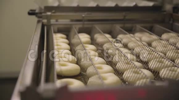 在一个小镇的甜甜圈面包店制作甜甜圈的程序甜甜圈在油炸锅里油炸场景准备过程视频的预览图
