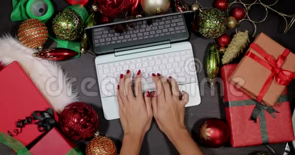 双手在圣诞装饰之间使用笔记本电脑视频的预览图