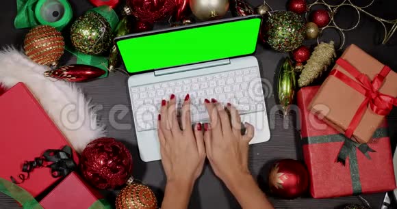 手在圣诞装饰品之间使用笔记本电脑视频的预览图