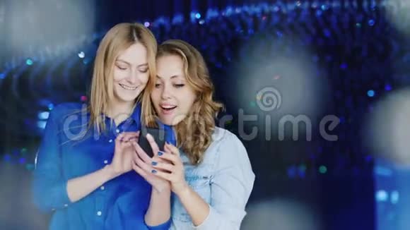 两个年轻的女性朋友在夜总会用电话积极的情绪视频的预览图
