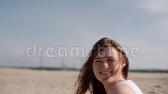 坐在沙滩上的女孩快乐的女孩在风中长出头发视频的预览图
