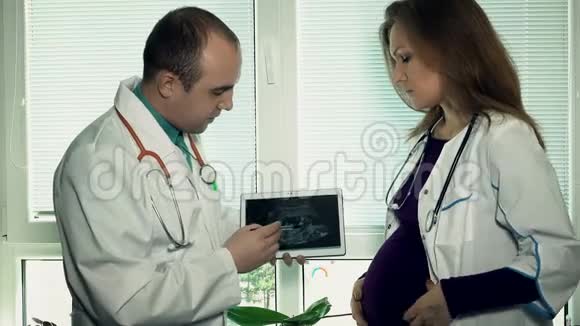 医生在超声波照片中解释女同事未出生孩子的问题视频的预览图