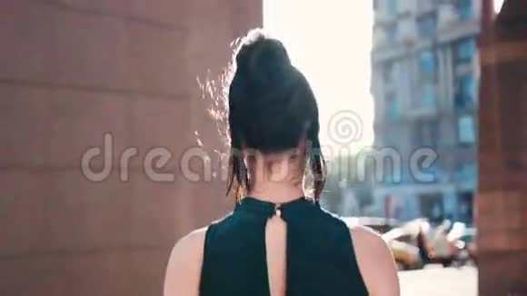 一位身着优雅服装的漂亮黑发女人从大楼里走出来转过身对着镜头分享一个视频的预览图