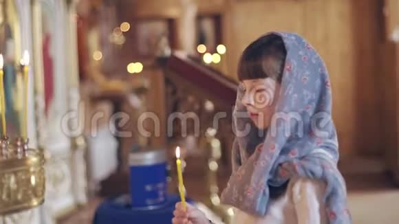 一个拿着蜡烛在东正教圣像前祈祷的女孩视频的预览图