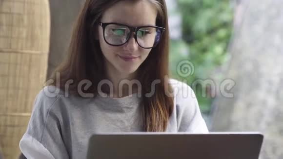戴眼镜的女人用笔记本电脑微笑女商人在度假期间在电脑上工作视频的预览图