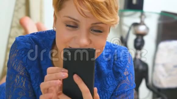 穿着蓝色连衣裙的金发美女在智能手机上发短信视频的预览图