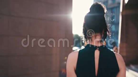 一位身着优雅服装的漂亮黑发女人从大楼里走出来转过身对着镜头分享一个视频的预览图