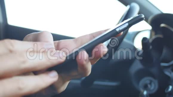 男人在车里拿着智能手机男人在智能手机上获得短信在线社交媒体传播生活方式视频的预览图