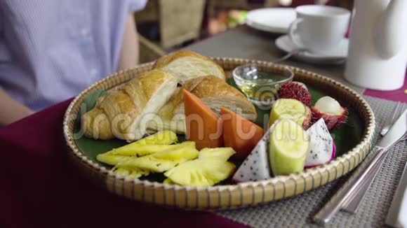 女性早餐吃热带水果牛角面包煎饼和蜂蜜视频的预览图