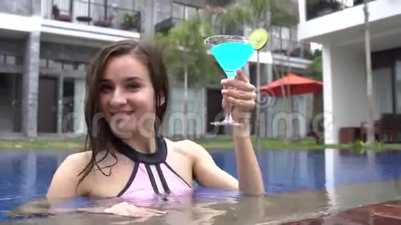 女人在豪华别墅里用蓝色的coctail玛格丽塔来拍摄和喝酒视频的预览图