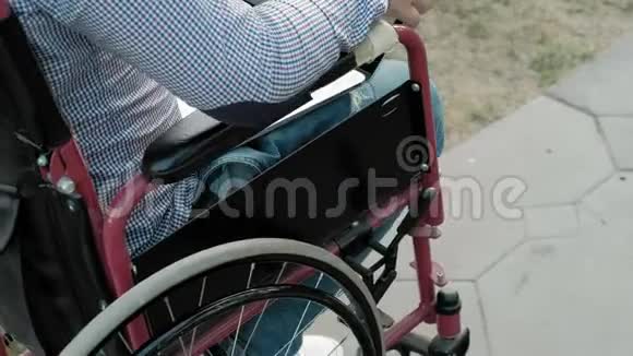 一个残疾人坐在轮椅上在公园里的笔记本电脑上工作视频的预览图