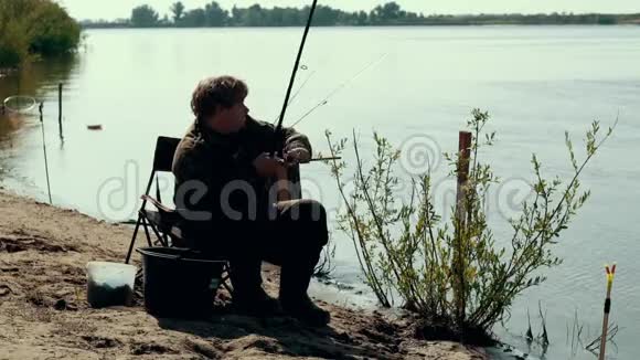 在河边钓鱼的时候年轻的渔夫在旋转鱼卷视频的预览图