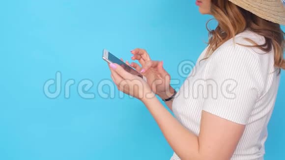 蓝色背景下使用手机的年轻女性视频的预览图