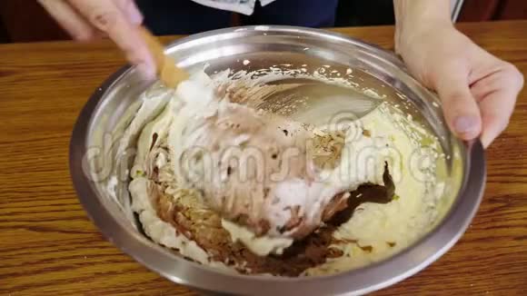 将奶油与巧克力混合在碗中的女人手的特写视频的预览图