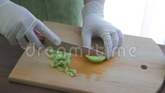 一个女人用一把刀在木板上切奇异果摄像机从左向右移动视频的预览图