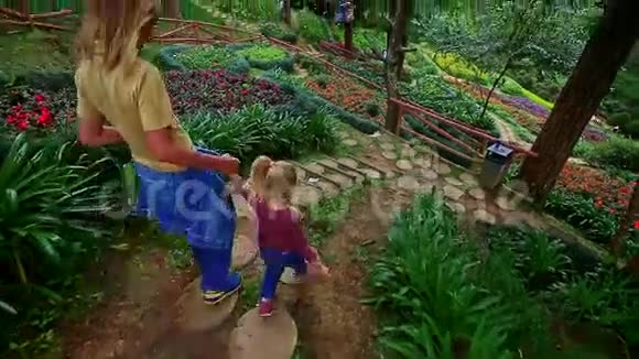 母亲小女孩爬上石阶在花坛中视频的预览图