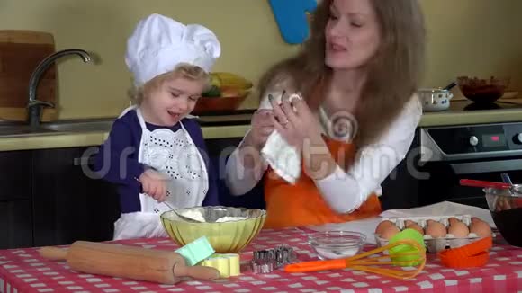 可爱的女儿和妈妈把面粉抹在鼻子上厨房里嬉戏的家庭女孩视频的预览图