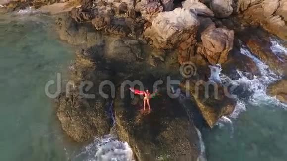 美丽的比基尼年轻女子站在石岸上高空飞离高清慢镜头视频泰国普吉岛视频的预览图