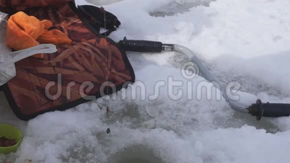 冬天钓竿河在冰洞附近冬天在冰上钓鱼竿河视频的预览图
