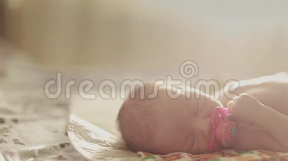可爱的新生儿躺在床上吮吸着一个臭虫视频的预览图