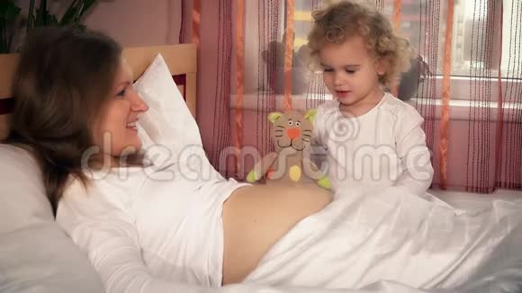带着怀孕妈妈和玩具猫在床上玩耍的小孩视频的预览图