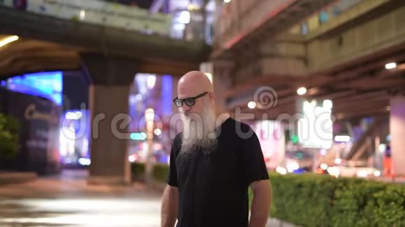 一个成熟的秃头游客在夜间探索城市街道视频的预览图
