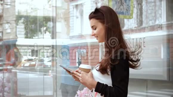 微笑的漂亮女孩拿着一杯咖啡看着电话视频的预览图