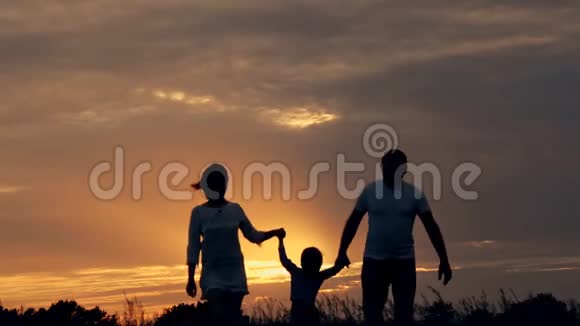 幸福的一家人在日落时在田野里奔跑夏夜一家人的剪影爱家庭的概念视频的预览图