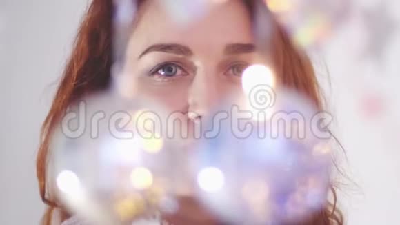 美丽神秘的女人透过花环的灯光看着镜头慢动作3840x21604k视频的预览图