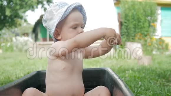 夏天巴拿马的一个可爱的孩子坐在花园里洗澡他玩水和手指视频的预览图